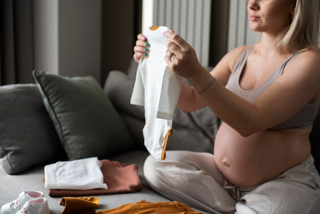 Close up pregnant woman looking at baby clothes