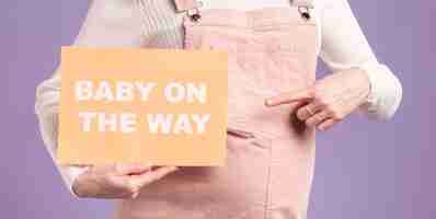 Free photo close-up pregnant woman pointing at paper with baby on the way message