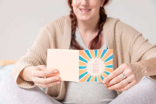 Close-up pregnant woman reading greeting card