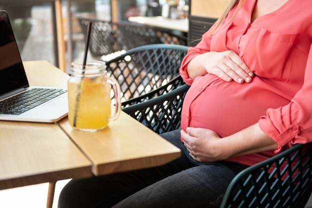 Close-up pregnant woman at a terrace with juice