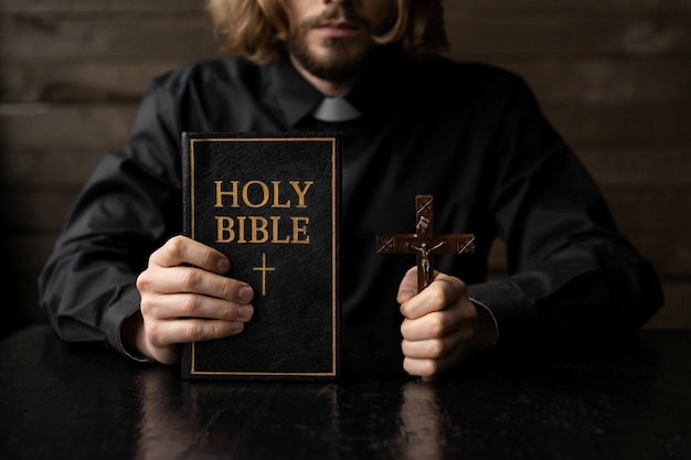 Close up priest holding cross and bible