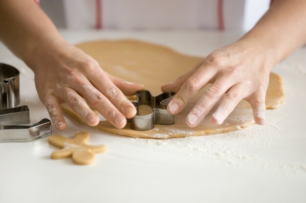 Close up of professional confectioner hands cutting gingermen