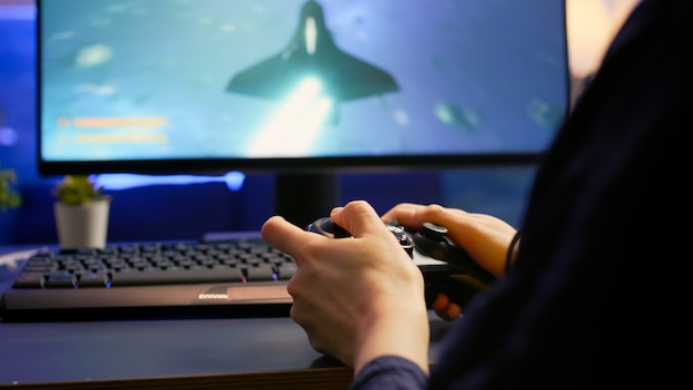 Free photo close-up of professional cyber gamer playing space shooter video game using wireless controller