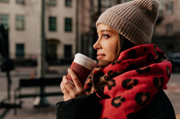 Close up profile portrait of charming pretty lady with beautiful eyes is drinking tea outdoor in sunshine