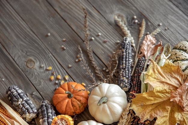 Free Photo close-up of pumpkin, corn and autumn leaves on a wooden background, top view, copy space.