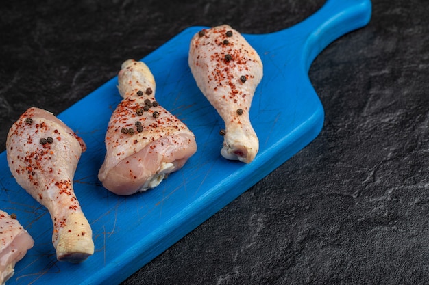 Free photo close up raw chicken drumstick on wooden board.