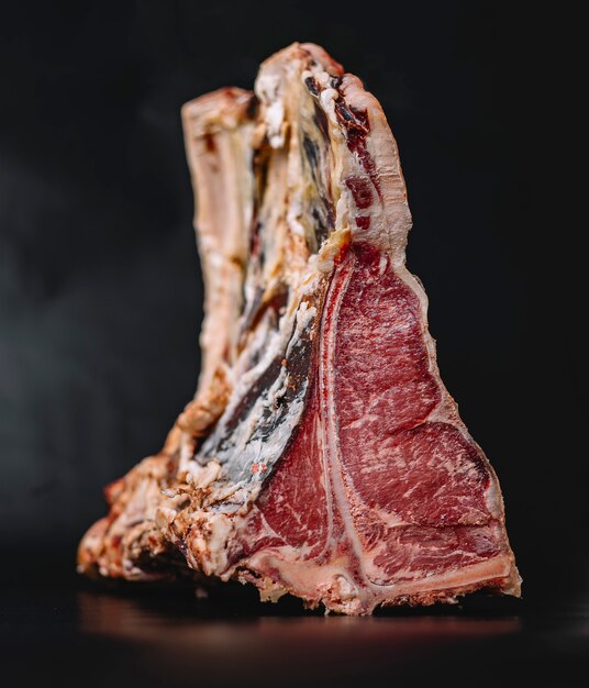 Close up of raw t-bone beef steak placed on navy blue