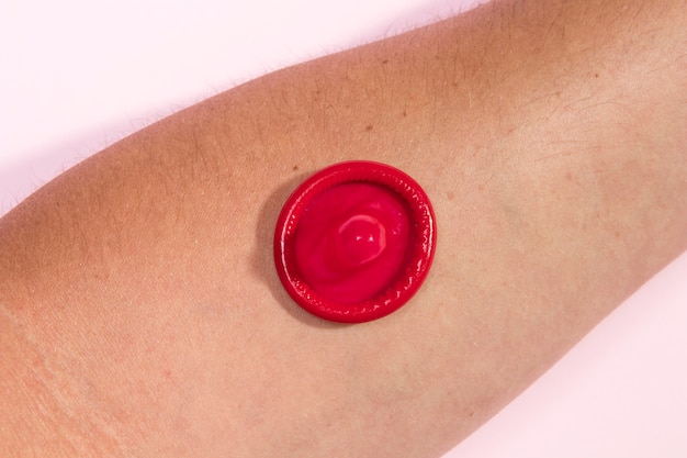 Free Photo close-up red condom on person's arm