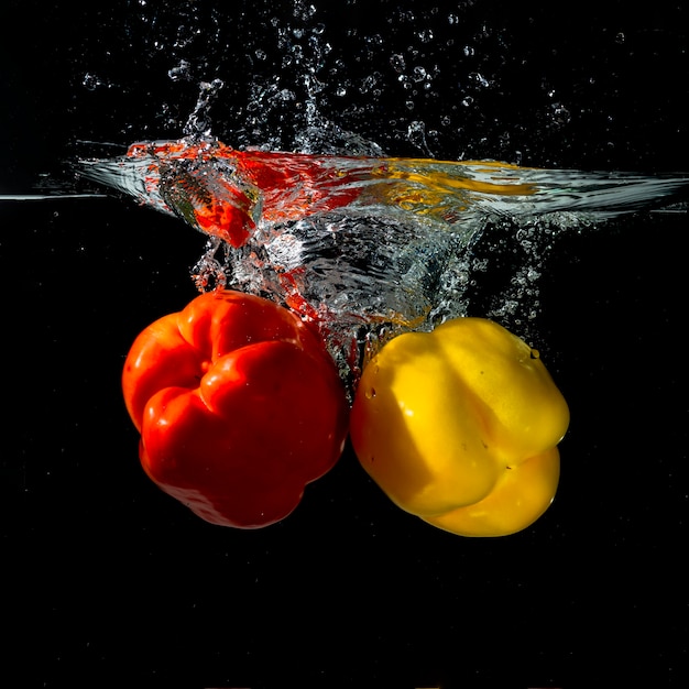 Close-up of red and yellow bell pepper splashing into water