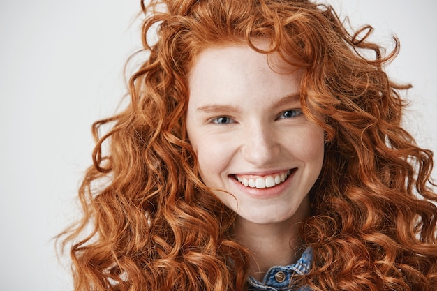 Close up of redhead beautiful girl with freckles smiling .