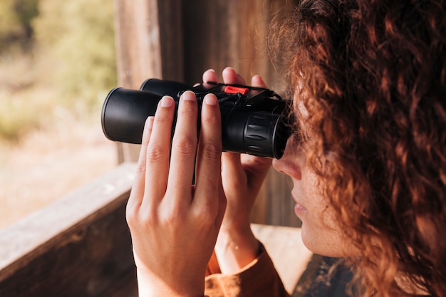 Free photo close-up redhead woman looking through binoculars