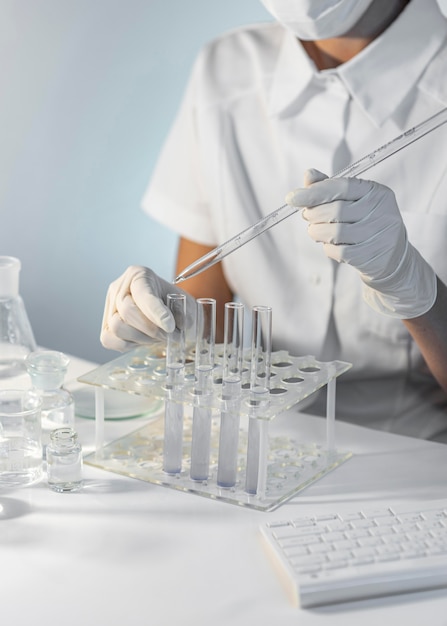 Close-up researcher holding pipette and tube