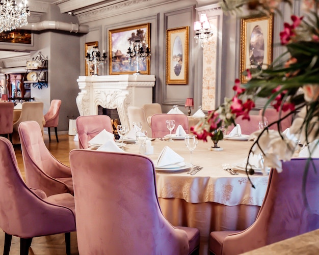 Free Photo close up of restaurant table with pink velvet chairs in grey painted hall with classic paintings