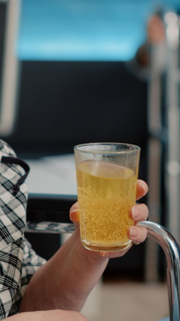 Close up of retired woman drinking effervescent medicine from glass of water sitting in nursing home. Medical specialist giving drink with vitamin and treatment to senior disabled patient