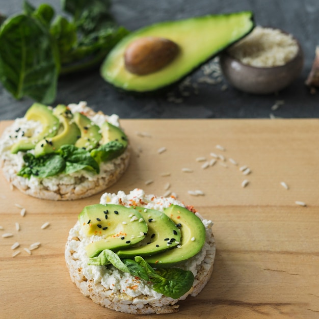 Free Photo close-up of rice cake with avocado slices; over wooden chopping board