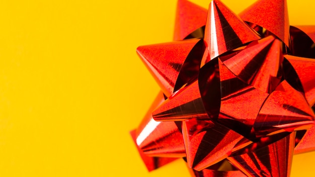 Free photo close-up of satin red ribbon bow on yellow background