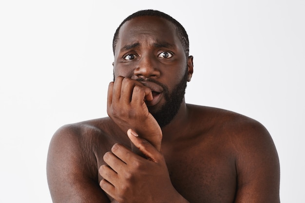 Close-up of scared young guy posing against the white wall