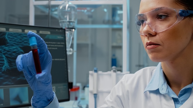 Close up of scientist analyzing lab vacutainer with fluid