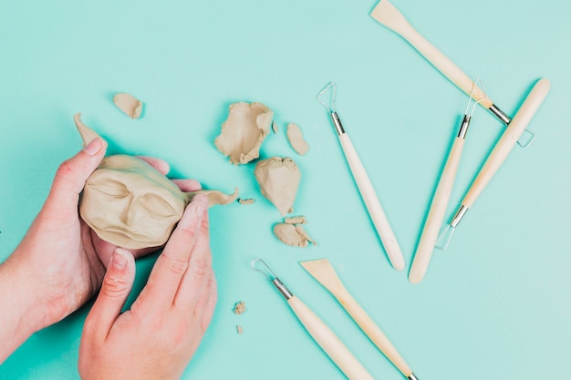 Free photo close-up of a sculptor artist creating sculpture face with clay on colored background