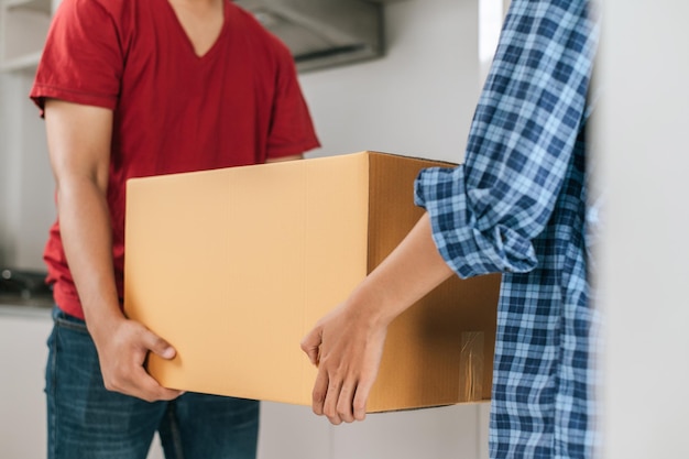 Close up Selective focus Young Asian couple help to holding heavy cardboard box walk into new house with happiness new house moving concept