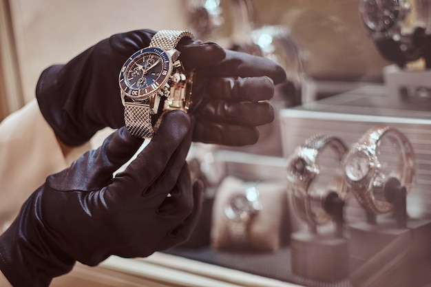 Close-up of the seller's hands in gloves shows the exclusive men's watch from the new collection in the luxury jewelry store