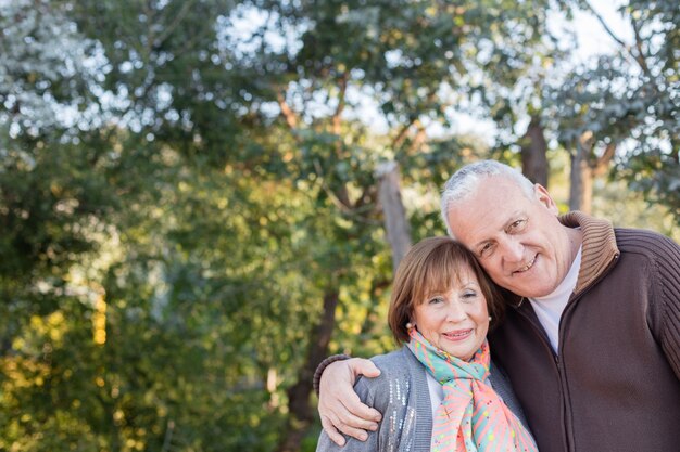 Close-up of senior couple hugging with trees background