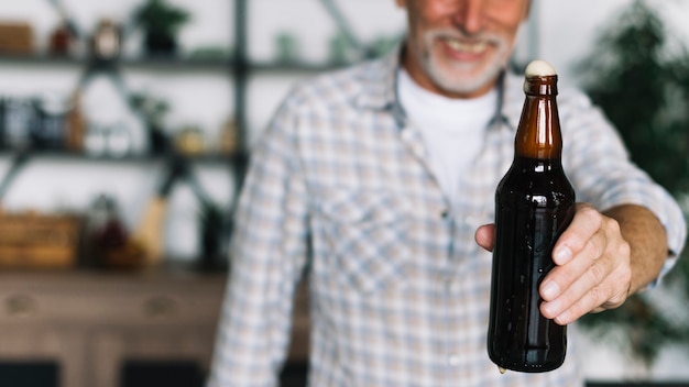 Free photo close-up of senior man offering beer bottle