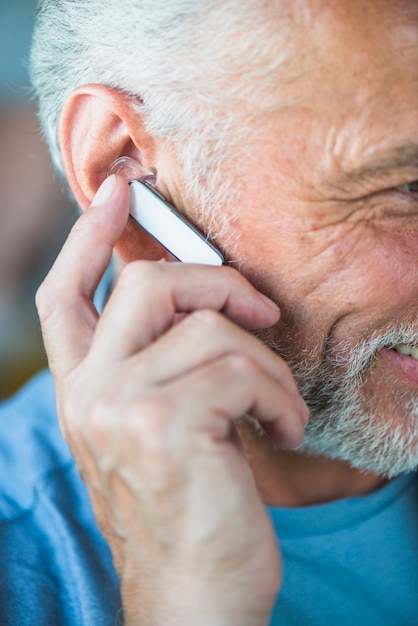 Close-up of senior man's hand on bluetooth headset on his ear