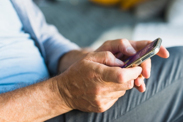 Free Photo close-up of senior man's hand browsing on mobile phone