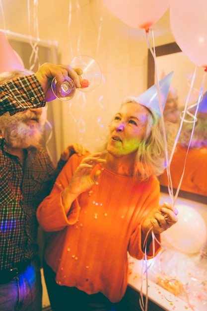 Close-up of a senior man throwing confetti from martin glass on his wife's body