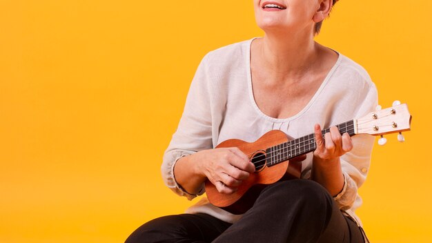 Close-up senior woman playing guitar