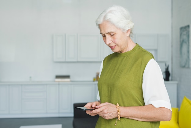 Close-up of senior woman using mobile at home