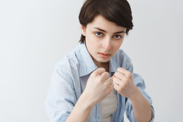 Close-up of serious-looking girl tomboy raising fists for fight, boxing and looking daring