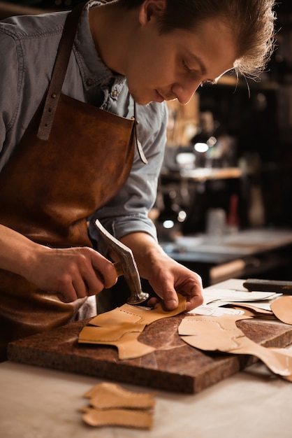 Close up of a shoemaker man working with leather