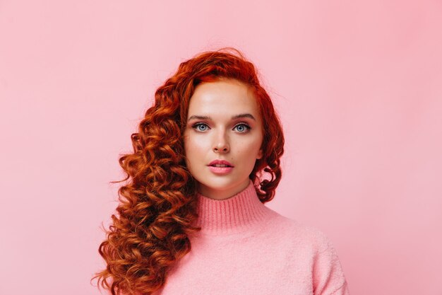 Close-up shot of curly woman in pink sweater