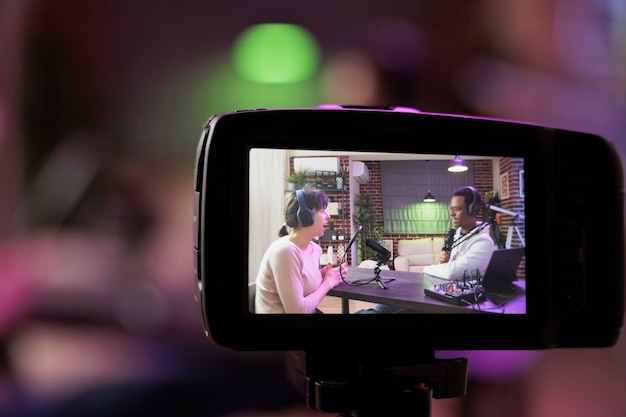 Free Photo close up shot focused on preview image on professional camera with podcast host and african american guest enjoying conversation in blurry background professional recording equipment in home studio