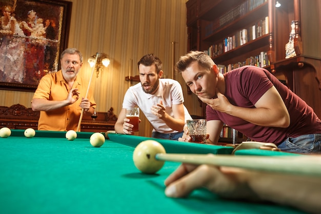 Free photo close-up shot of a man playing billiard. caucasian model carefully and strenuously aiming by cue in ball. game concept