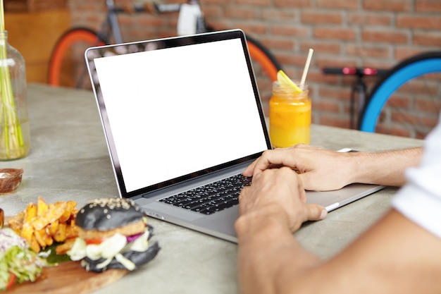 Close up shot of man's hands on keyboard of open generic laptop. Male student studying online on his notebook computer