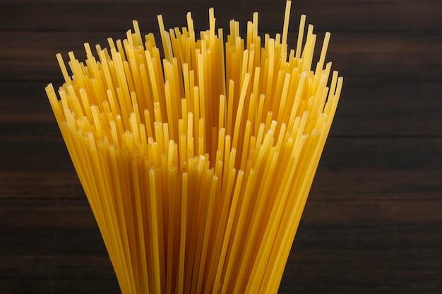 Close-up side view raw spaghetti on a wooden surface