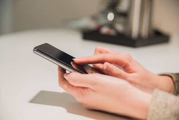 Close up of smartphone in hand. Close up of a woman hand holding a smartphone and texting. womans hands typing on smartphone over wooden brown table