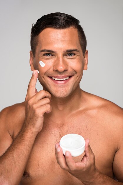 Close-up smiley man holding face cream