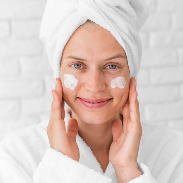 Close-up smiley woman using facial cream