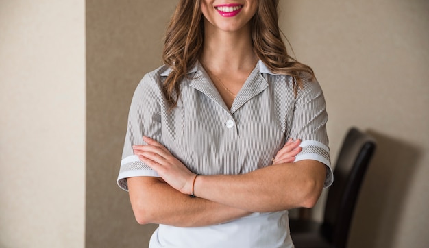 Free photo close-up of smiling chambermaid standing with her arms crossed