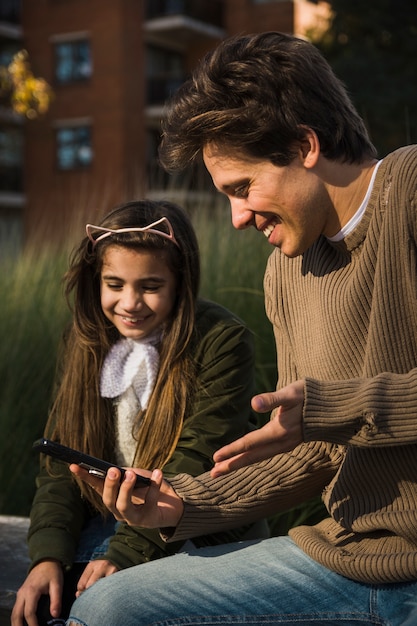 Close-up of smiling father and daughter looking at smart phone