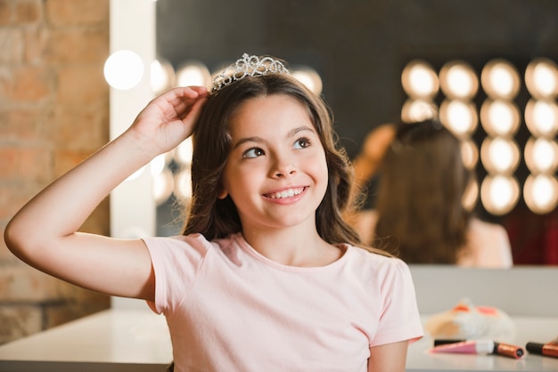 Free photo close-up of smiling girl wearing crown daydreaming