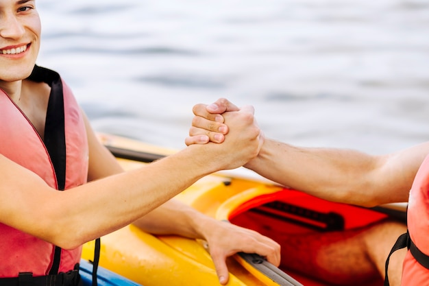 Close-up of smiling male kayaker holding friends hand