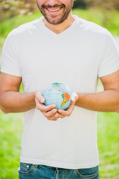 Free Photo close-up of smiling man holding globe in hand