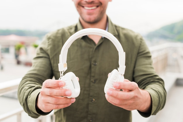 Close-up of smiling man showing white headphone