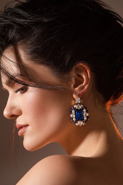 Close up of smiling pretty lady posing while demonstrating designer jewelry. Beauty concept