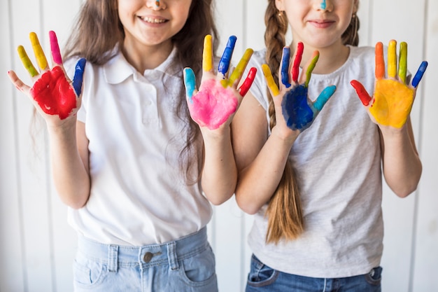 Free Photo close-up of smiling two girls showing their painted hands with color